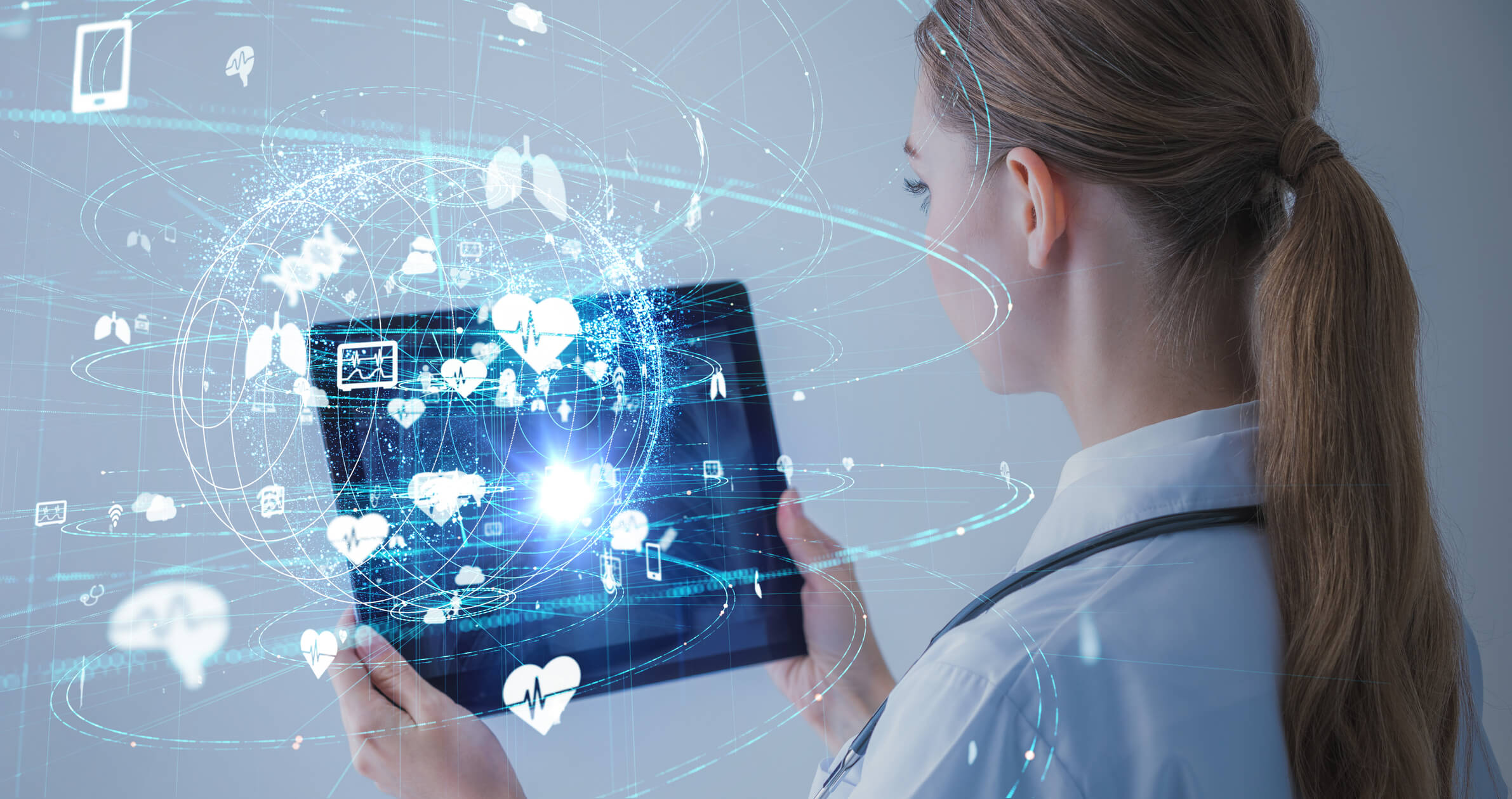 healthcare professional holding tablet with electronic futuristic symbols emitting from it